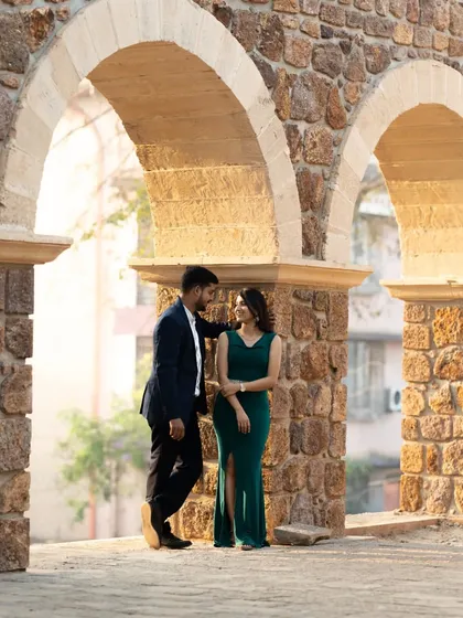 A romantic pre-wedding photo of a couple framed by stone arches, creating a timeless and classic portrait.