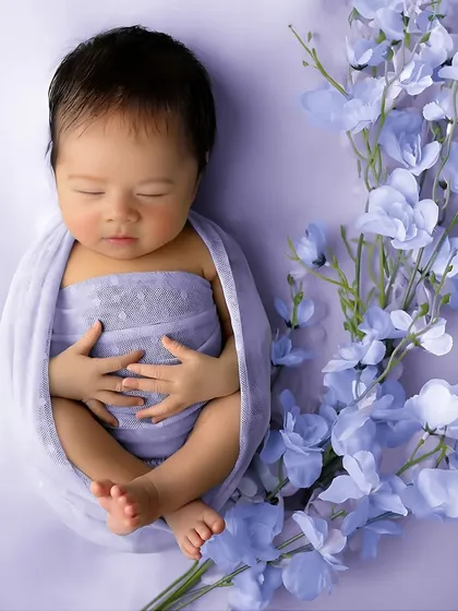 A simple and elegant potato sack pose with a sprig of lavender flowers. This minimalist approach keeps the focus on the baby's perfect form and peaceful expression.
