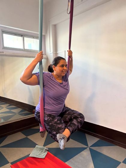 Finding joy in the journey. This student’s smile captures the supportive and encouraging atmosphere we cultivate in every aerial yoga class.