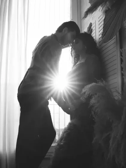 A black and white version of a beautiful sun-flare silhouette. The monochrome effect adds a timeless and romantic quality to this intimate couple's portrait.