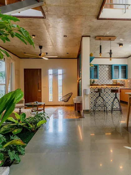 Another view of 'The Valley' home, highlighting the seamless flow between the living, dining, and kitchen areas. The exposed concrete ceiling and natural light from skylights create a modern yet earthy atmosphere.