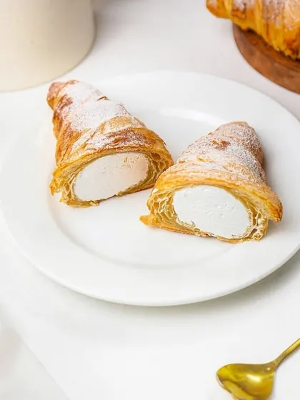 A top-down view of the cream-filled pastry horns, arranged neatly on a plate with a golden spoon. This flatlay style is modern and perfect for social media feeds.