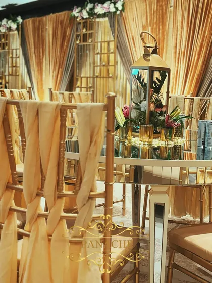 A detail of the guest table setup, showing the mirror-top table, floral centerpiece in a lantern, and the beautifully draped chairs.