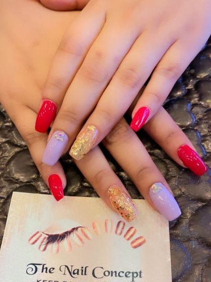 A playful and colorful set of square nails. The design features a mix of red, lavender, and gold glitter nails, with small crystal details for extra shine.