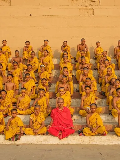 A moment of quiet contemplation as young Batuks, or student monks, sit in perfect formation on the steps of a Varanasi ghat. The single figure in red is their teacher, a beacon of knowledge.