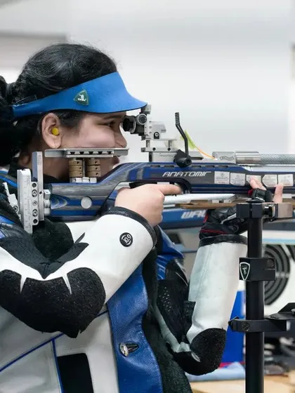 A female rifle shooter in full competition gear, demonstrating perfect form and concentration during a national-level event hosted at our academy.