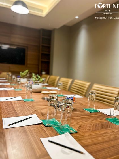 The table is set for success. This perspective shows the length of the boardroom table, ready with notepads, pens, and water, illustrating my preparedness for your team's important discussions.