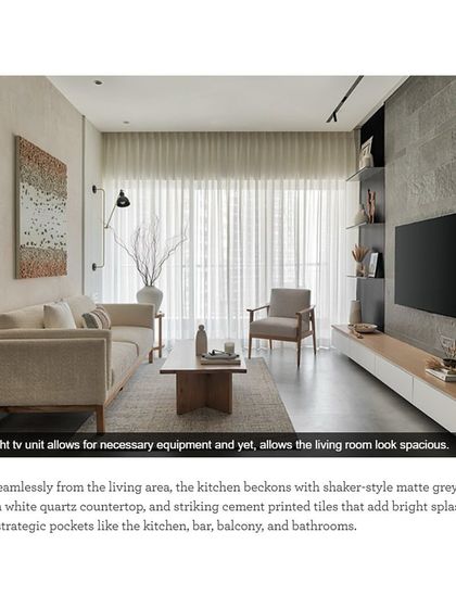 A low-height TV unit allows for necessary equipment while keeping the living room looking spacious. This design choice is part of a seamless flow from the living area to the kitchen.