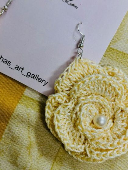 A close-up of my cream-colored rose earring, handcrafted from cotton thread. I've added a small pearl in the center for an elegant touch.