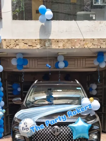 A car decorated to welcome a new baby boy, featuring a blue and white balloon arrangement and an "It's a Boy" foil balloon.