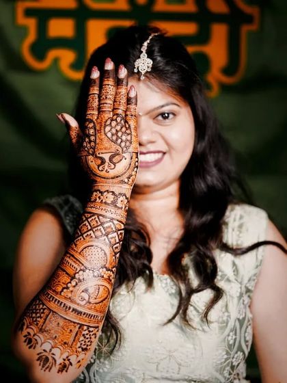 A classic bridal pose, with the intricate mehendi on one hand framing the bride's happy smile.
