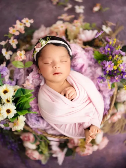 For this shot, I used a simple pink swaddle to create a beautiful contrast with the surrounding purple and white flowers. This classic newborn pose is always a favorite among parents.