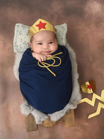 A tiny Wonder Woman. This newborn girl is ready to save the world, complete with her iconic tiara and cuffs.