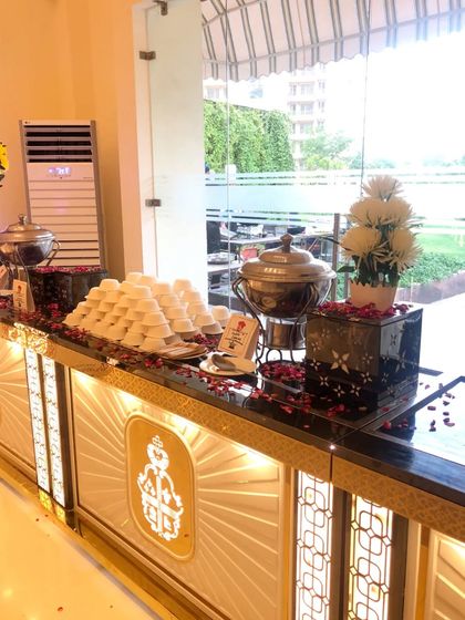 An elegant dessert and soup station at an indoor wedding event. The illuminated counter with gold accents and neatly arranged serveware creates a sophisticated and inviting look.