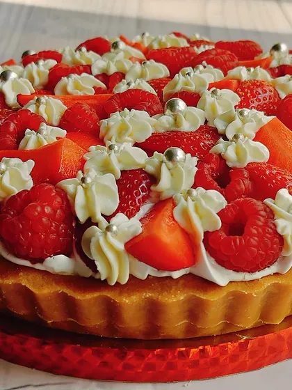 A close-up of my raspberry and strawberry cheesecake tart, showing the juicy fresh berries and silver pearls that add a touch of elegance.