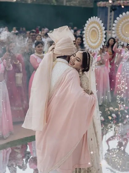 A hug that says forever. This candid moment captures the pure joy and relief after the varmala exchange, with cold pyros sparkling in the background, adding to the magic.