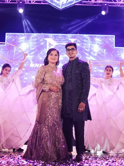 The couple making a grand entry on stage, surrounded by performers. The bride looks confident and stunning.