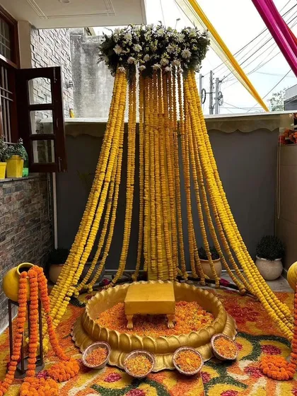 We can transform even small spaces like a balcony into a beautiful ceremony spot. This intimate Haldi setup features a canopy made of dense marigold strings, creating a perfect, private space for rituals.