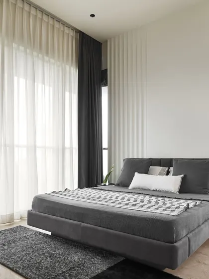 The custom floating bed in the Slate Bedroom is upholstered in a dark grey fabric, contributing to the room's calming, monolithic feel. The curved fluted wall detail behind it adds a subtle texture that catches the light beautifully.