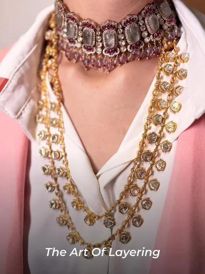 The art of layering extends beyond traditional wear. Here, a delicate polki choker is styled over a collared shirt with a cascading long necklace, creating a chic, Indo-western look.