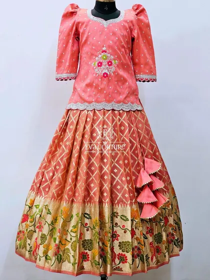 A lovely peach-colored lehenga with a Paithani-style floral border. The blouse has three-quarter sleeves and delicate embroidery.