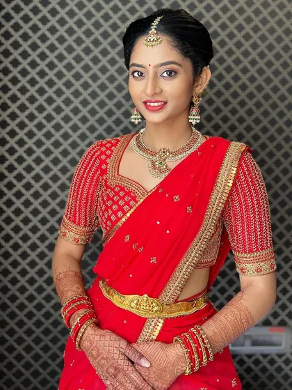 A happy portrait of Manya in her red ensemble. The hand-embroidered blouse features a classic sweetheart neckline and detailed work on the sleeves.