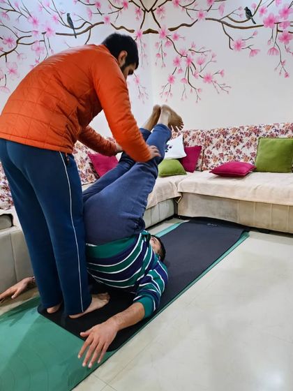 Teaching is a two-way street. Here, I'm assisting a student in Halasana (Plow Pose), ensuring his neck is safe and his spine is getting a full, beneficial stretch.