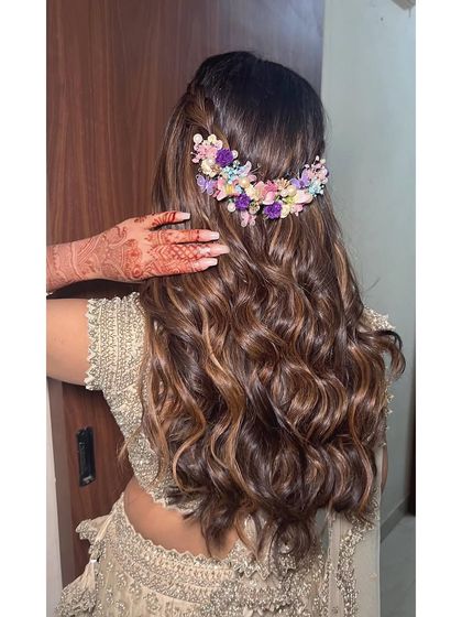 For this engagement look, I created voluminous waves with a half up twist. The style is completed with a beautiful pastel floral hairpiece that perfectly matches the bride's outfit.