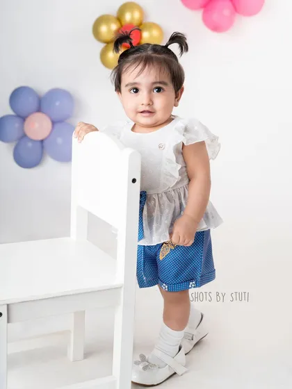 A playful and colorful outfit for a fun toddler portrait. The background with balloon flowers complements her look without overpowering her charming presence.