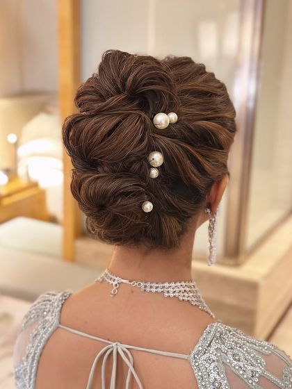 A detailed shot of the pearl-adorned messy bun, showing the texture and placement of each pearl to create a look that is both intricate and seemingly effortless.