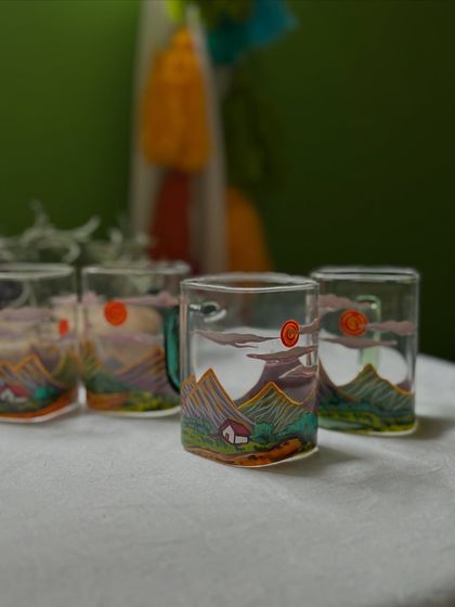 A close-up of the mountain scene on the square glass mugs, complete with a tiny house nestled in the valley.