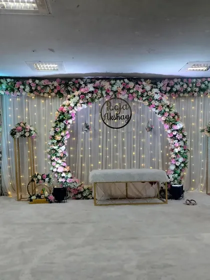 This is one of our most popular engagement and sakharpuda setups. The full floral arch, elegant white drapes with fairy lights, and a custom name hoop create a perfect, photo-ready backdrop for your special day.