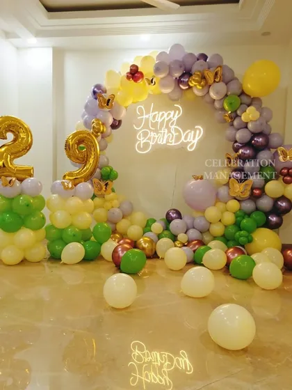 A vibrant and fun balloon arch for a 29th birthday. I used a mix of purple, green, yellow, and metallic balloons, with butterfly accents and a neon sign to create a cheerful photo corner.