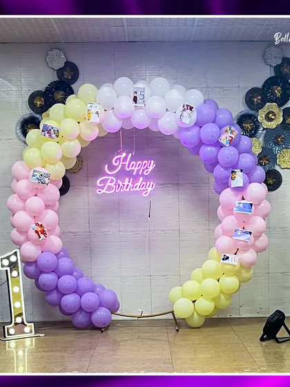 A rainbow of memories for a first birthday. This unique circular balloon arch in pastel rainbow colors is personalized with photos from the baby's first year, creating a truly special and sentimental backdrop.