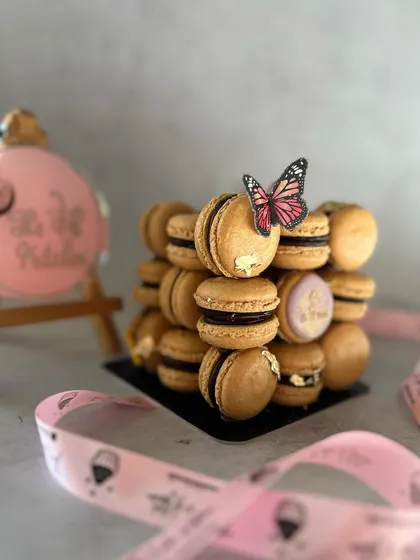 A close-up view showing the texture of the macaron shells and the shimmer of the edible gold leaf. I ensure every detail is perfect.