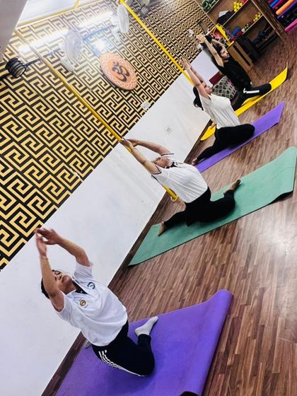 A dynamic shot of the class moving through a flowing vinyasa sequence. Each person is on their own mat, but we are all connected by our breath and movement.