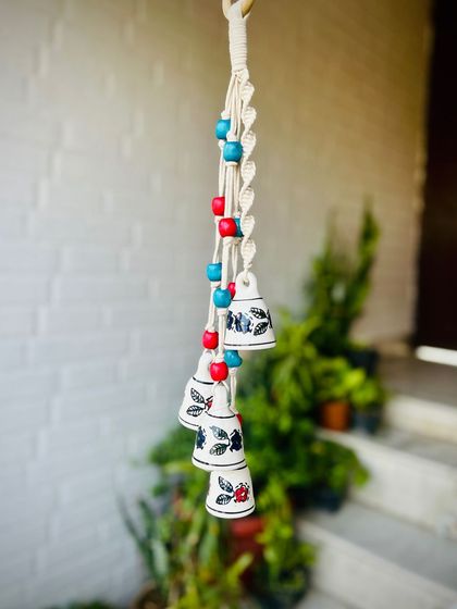 A close-up of our 'Symphony Chimes' in the 'Gulmohar' color variant. The intricate macrame knots, colorful wooden beads, and hand-painted ceramic bells make these a perfect gift for any occasion.