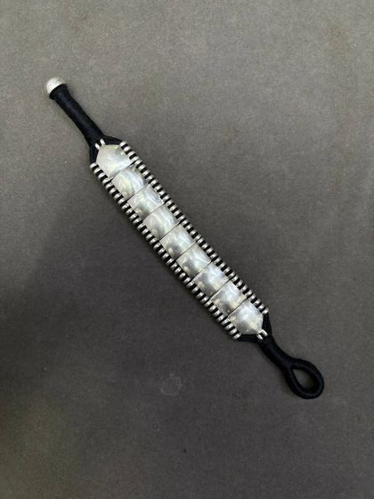 Another view of the woven silver bracelet on a black thread, showing the adjustable loop closure.