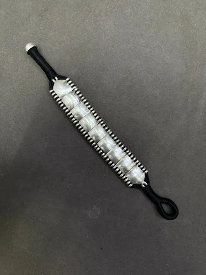 Another view of the woven silver bracelet on a black thread, showing the adjustable loop closure.
