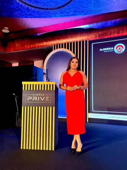 Posing by the podium at the Ajmera Privé event, ready to welcome guests.