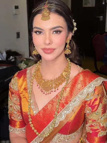 A portrait showcasing the beautiful contrast between the warm-toned saree and the soft, neutral makeup. The look is timeless and elegant.