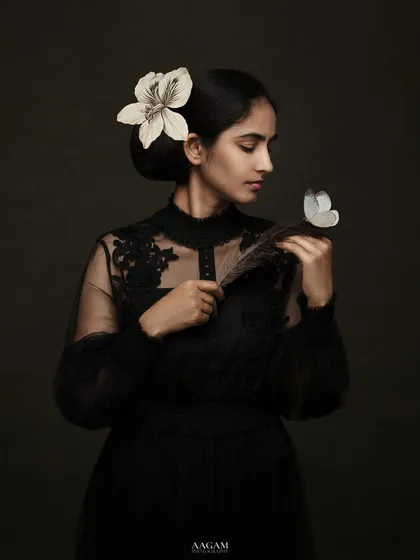 You are art. This portrait, with the subject in a black lace dress holding a feather and flower, is a story of elegance and introspection.