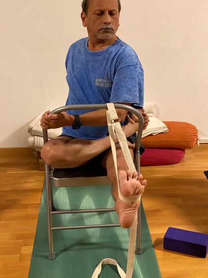 A seated hip-opening pose on a chair.