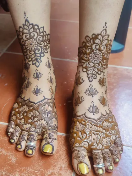 Another angle of the same floral and lotus foot design, showing the fresh henna paste.