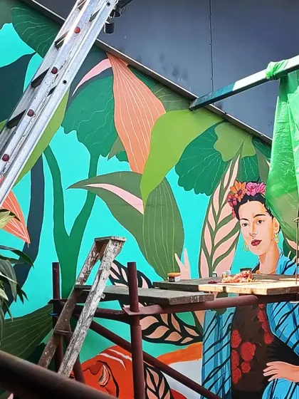Fully sending it. An in-progress shot from a different angle, showing the scaffolding and the sheer height of the Frida mural. We're not afraid to climb to create something amazing.