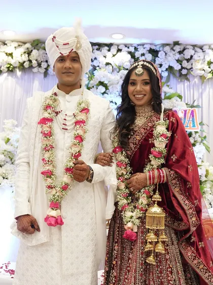 A classic portrait of a newly married couple in their stunning red and white wedding attire.