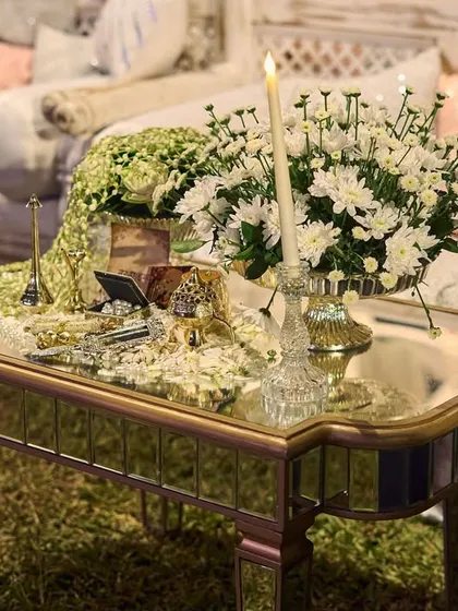A mirrored side table with a cascading arrangement of baby's breath and a single candle, reflecting the soft lighting and creating a poetic corner.