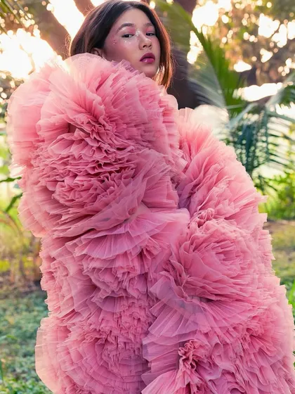The full, dramatic effect of the pink tulle coat. The soft, romantic makeup and hair prevent the look from being overwhelming and add to the dreamlike mood.