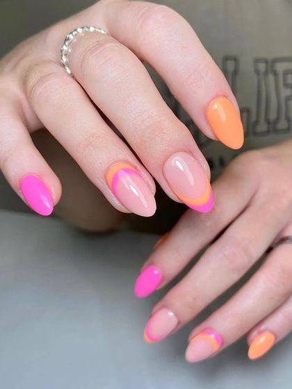 A bright and cheerful design for shorter nails, combining solid pink and orange nails with creative, colorful French tips.