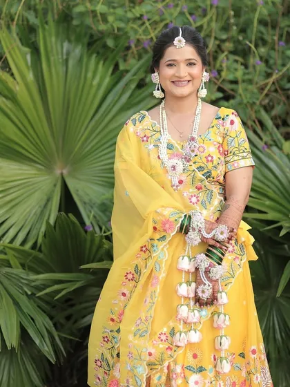 A full-length shot of the Haldi bride, showing how the floral jewellery complements her yellow embroidered lehenga.
